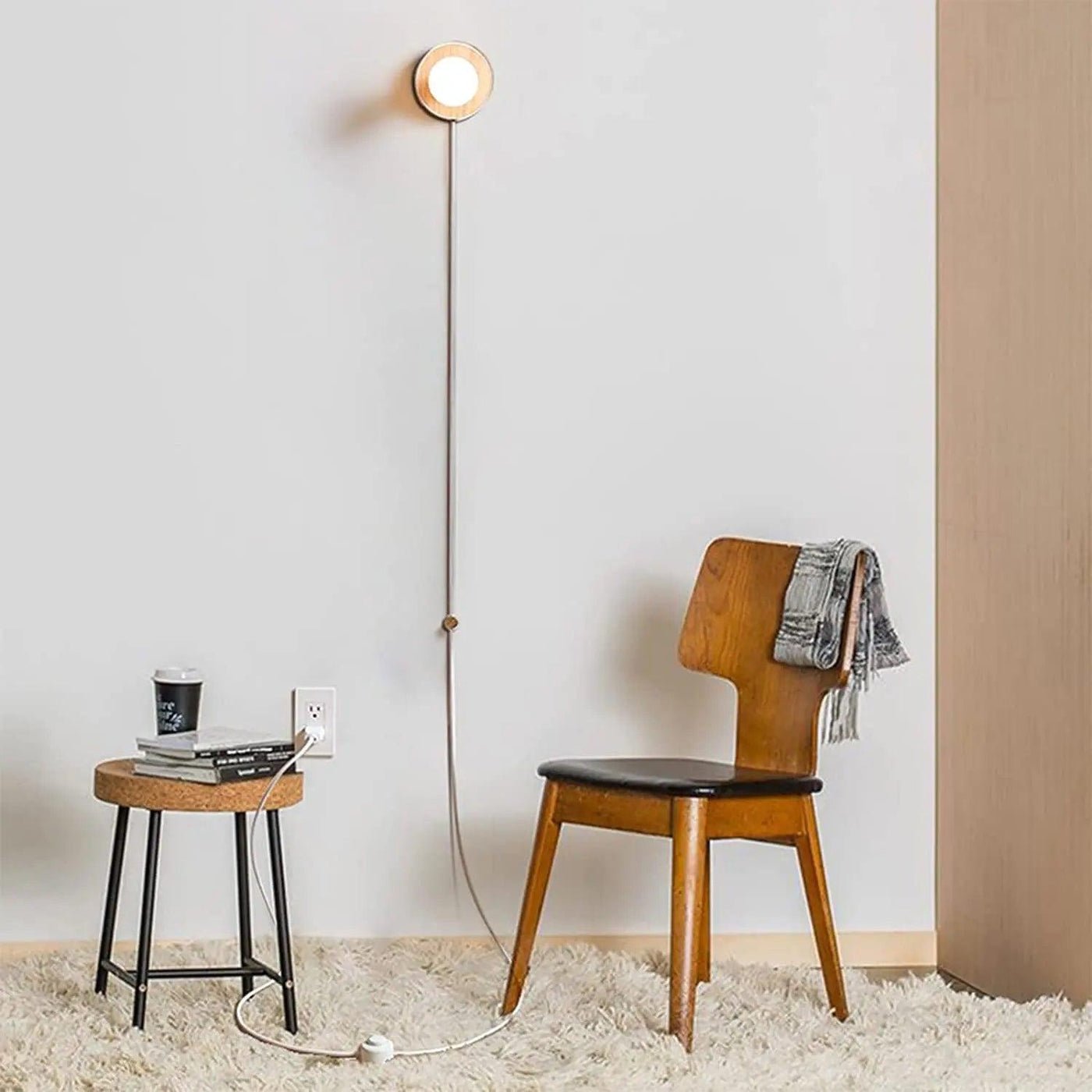 Bedside table with a lamp and a phone charging beside the bed in a guest room