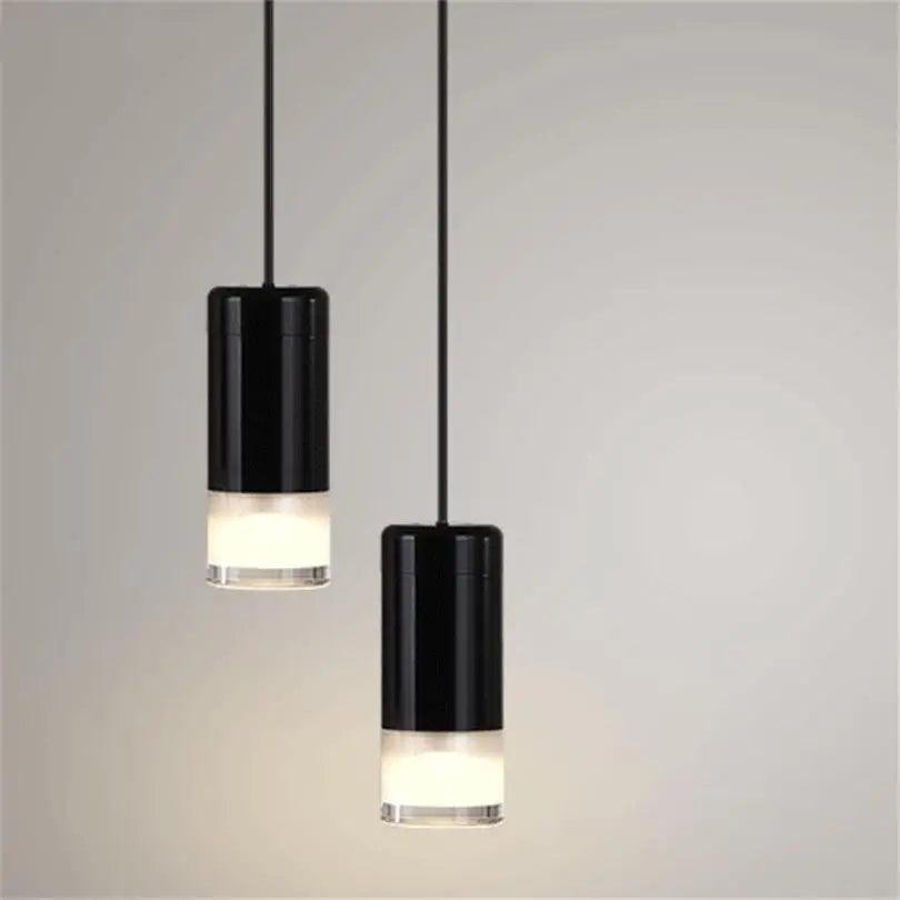 Black plug-in pendant light hanging over a bedside table in a rental apartment